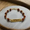 Close-up of the engraved gold name plate and rudraksha beads on the Printigly personalised rakhi bracelet