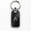 Small rectangle metal keychain in silver-black with a geometric logo